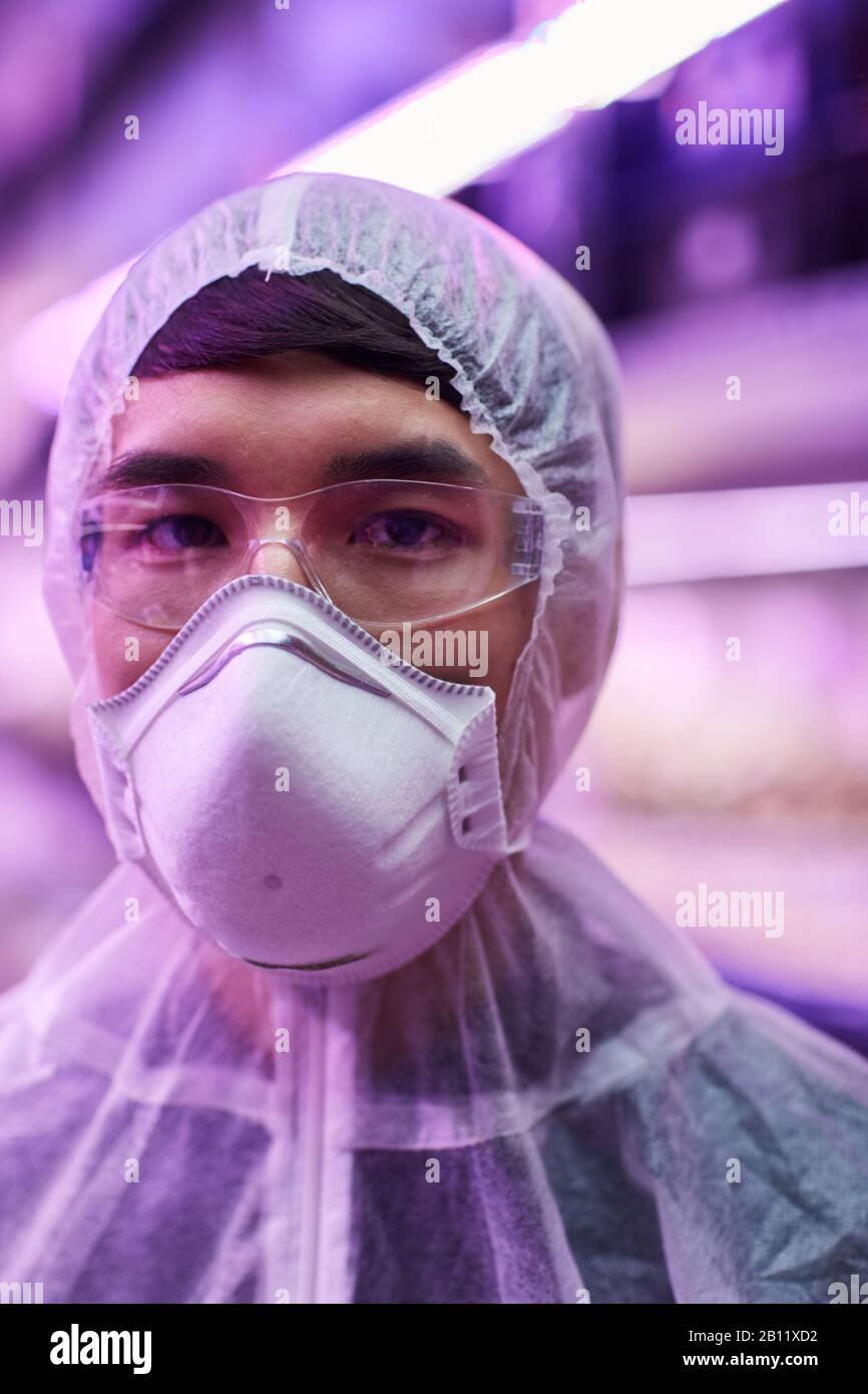 Ritratto di uomo asiatico che indossa indumenti protettivi mentre lavora in laboratorio chimico Foto Stock