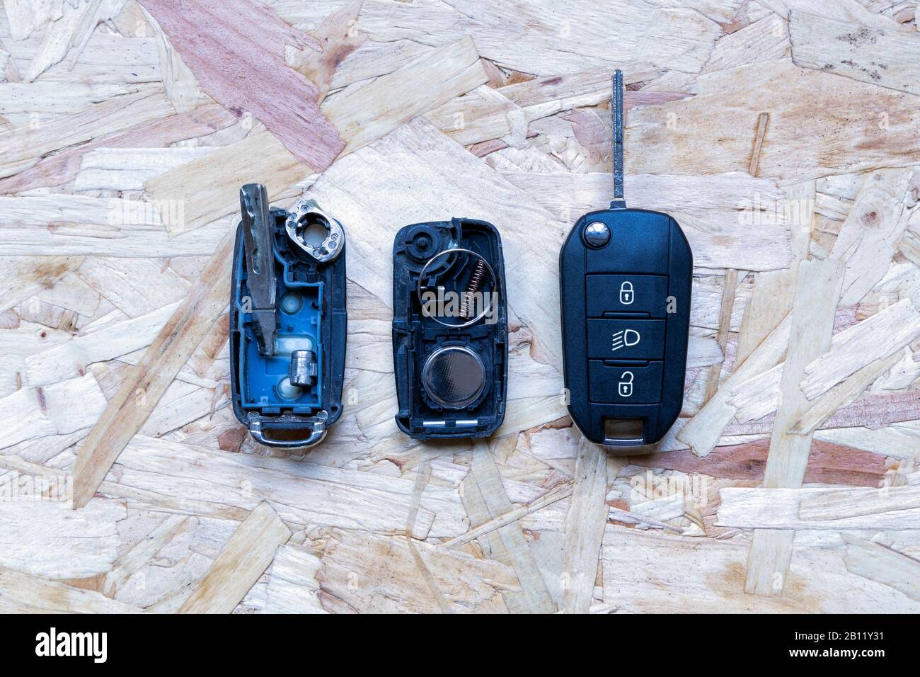 Telecomando rotto o danneggiato e chiave del nuovo veicolo su sfondo in legno astratto. Sostituzione della batteria del telecomando danneggiata o rotta di un veicolo Foto Stock