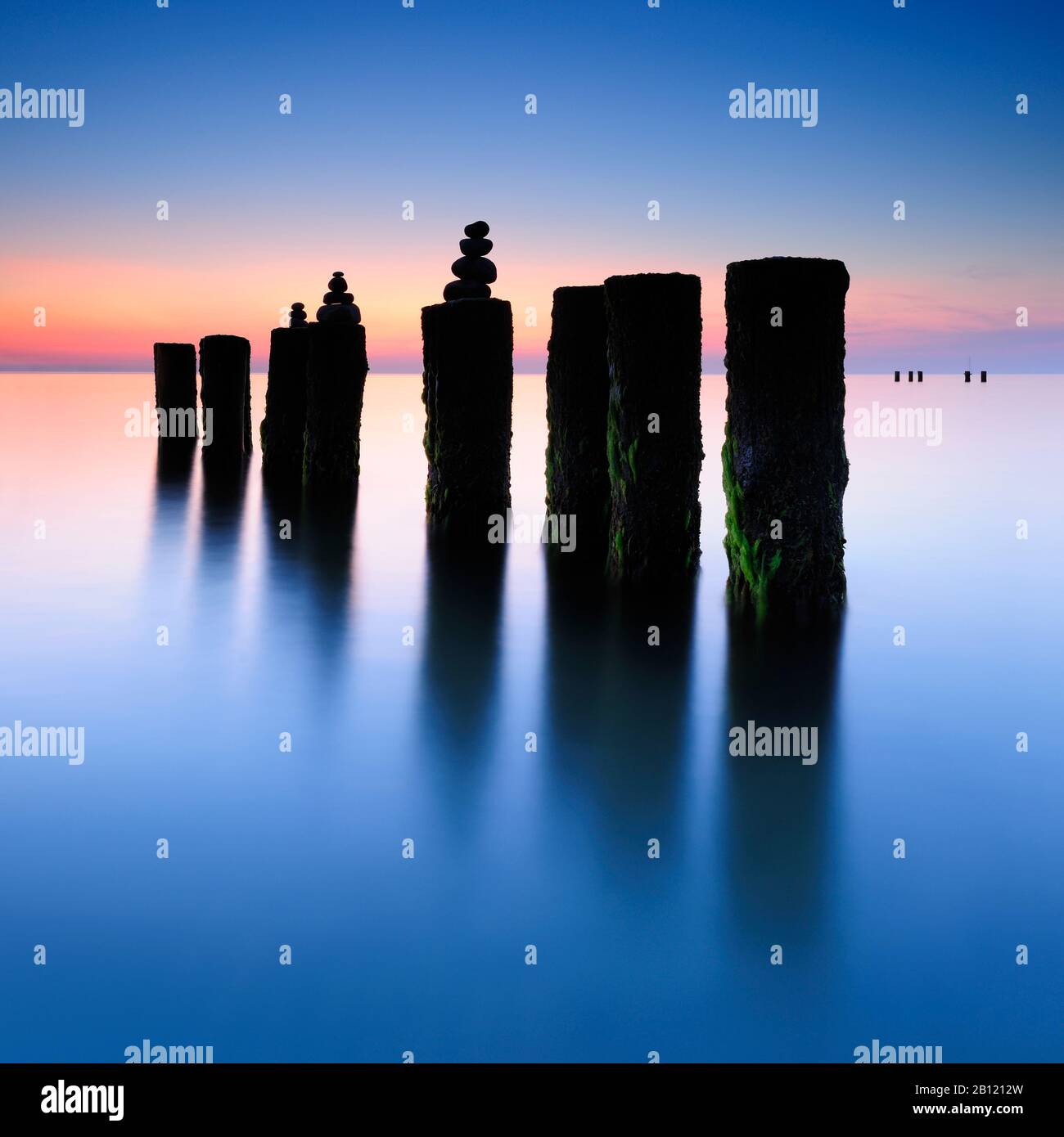 Tramonto sulla spiaggia ovest, piramidi di pietra sul vecchio groyne, Darß, Mar Baltico, Meclemburgo-Pomerania occidentale, Germania Foto Stock