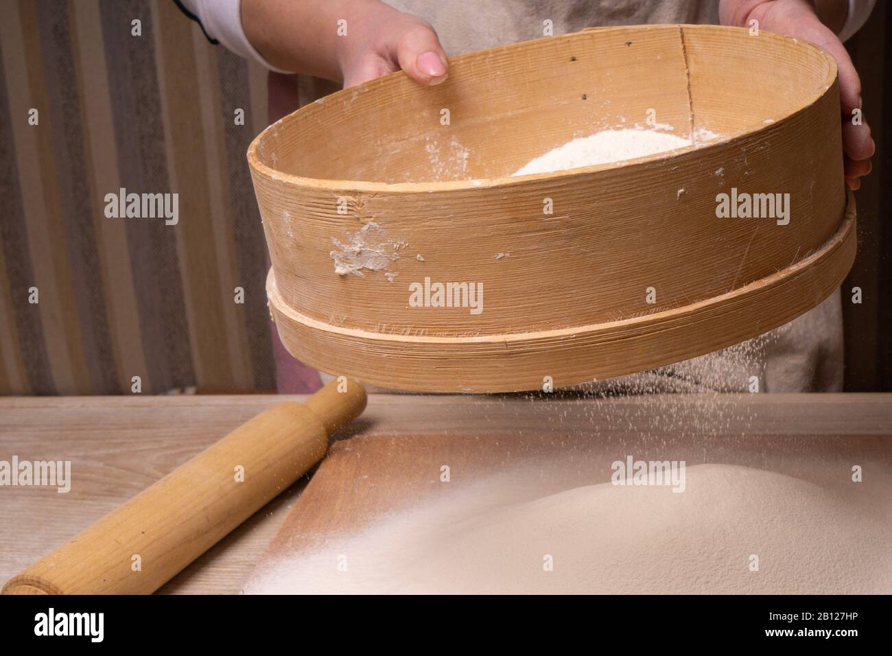 Una donna setacciò la farina attraverso un setaccio. Tagliere compensato,  setaccio di farina di legno e spina di laminazione di legno - attrezzi per  fare l'impasto Foto stock - Alamy