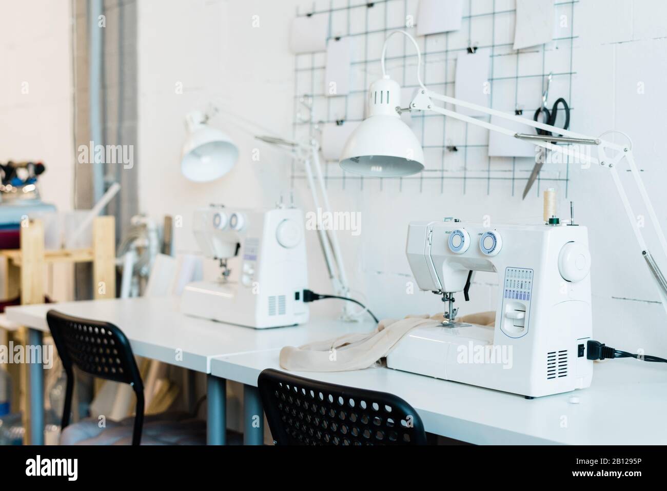 Luogo di lavoro di seamstress contemporaneo con sedia, scrivania, lampada e macchina da cucire Foto Stock