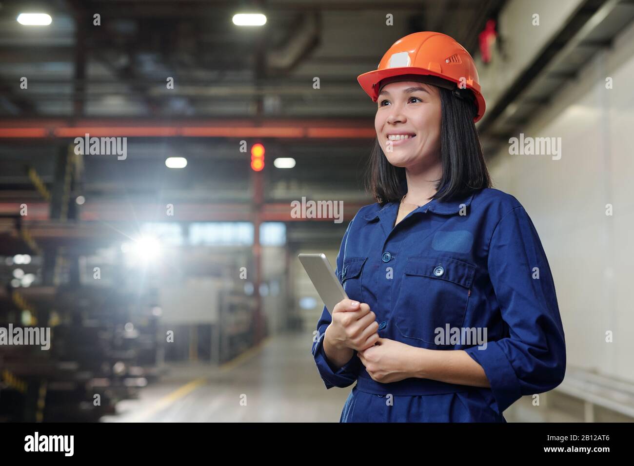 Allegro giovane femmina wngineer con touchpad in piedi in officina Foto Stock