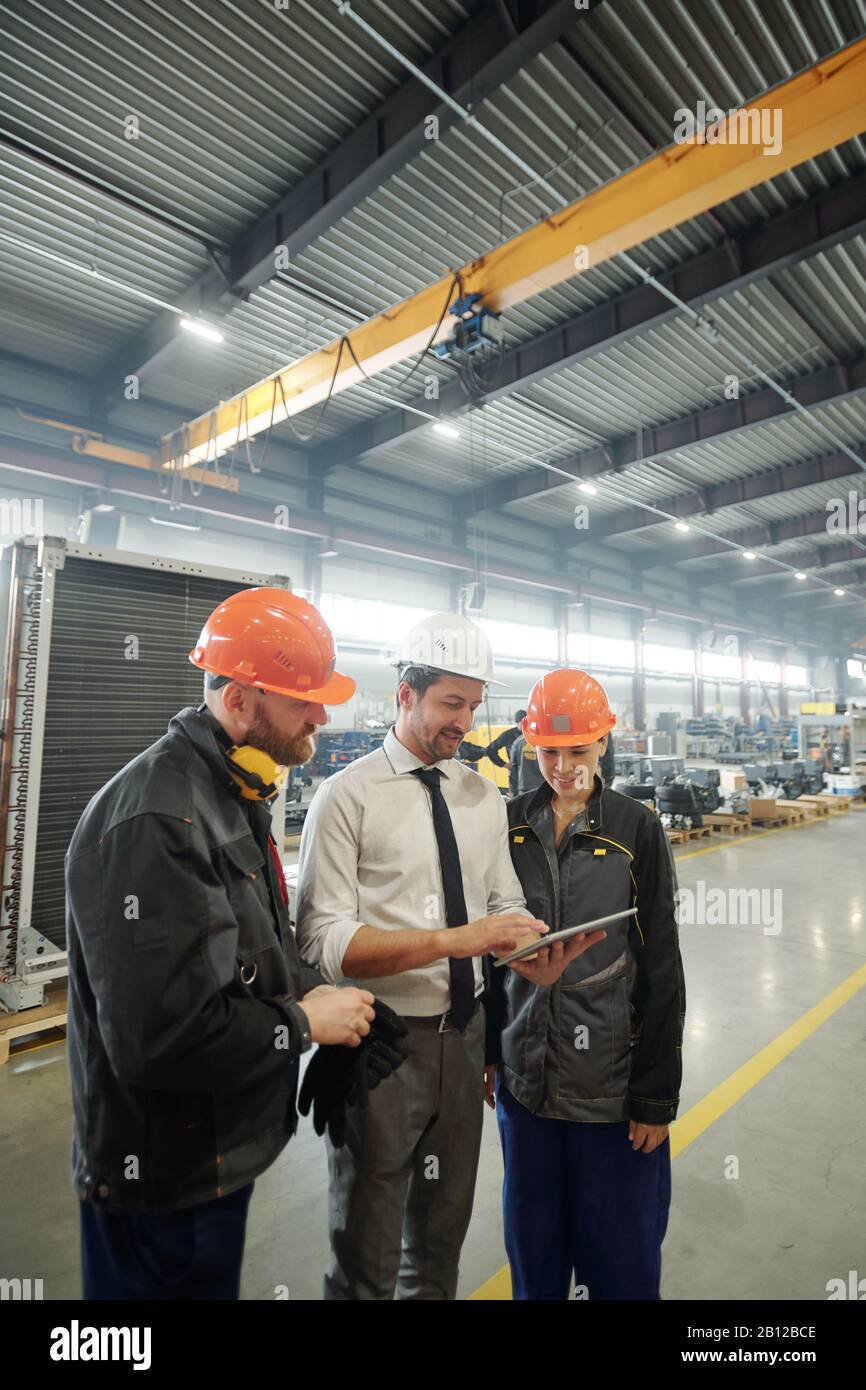 Tre giovani lavoratori di impianti industriali che discutono di schizzo tecnico sul lavoro Foto Stock