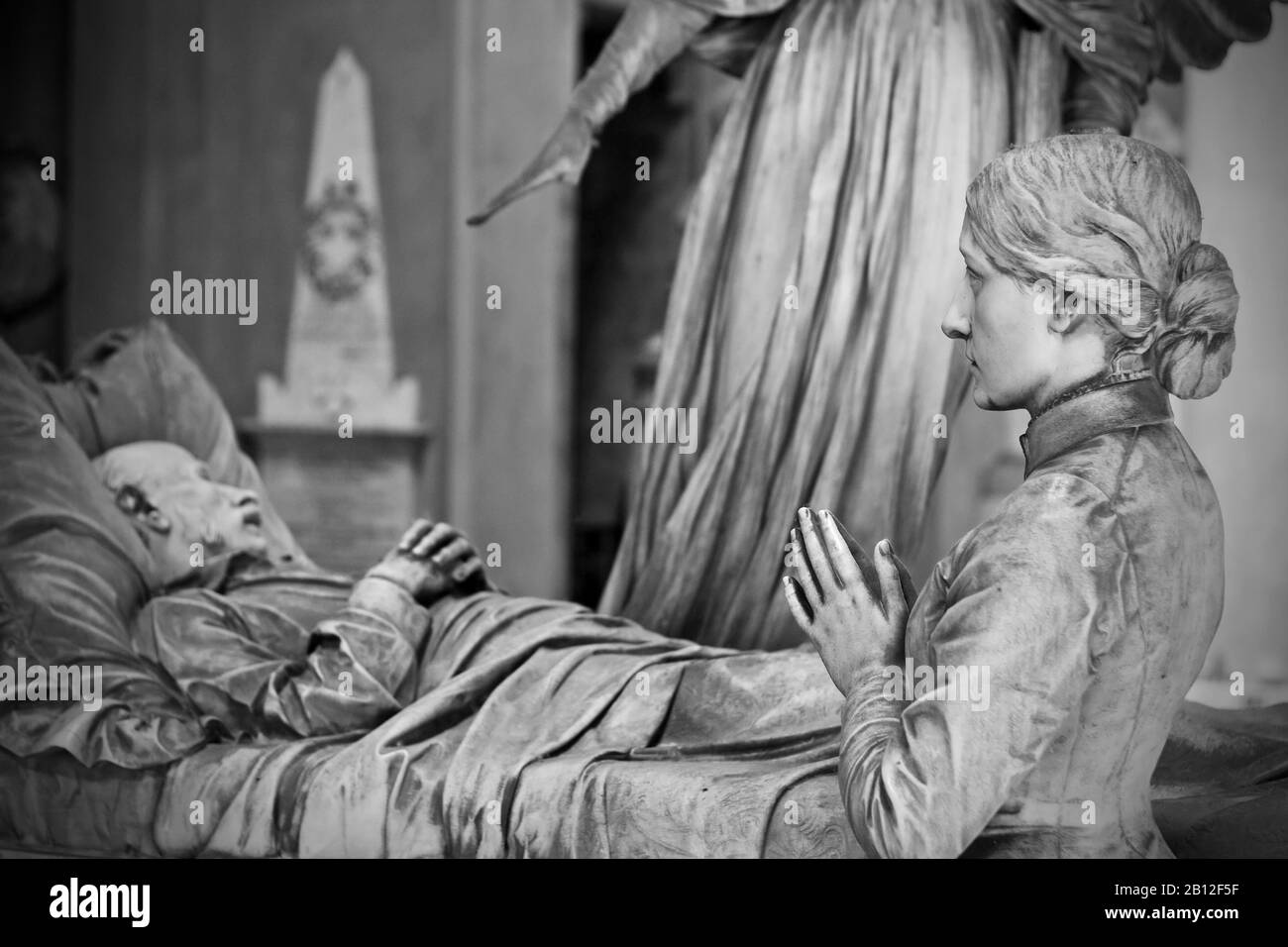 Statua di una donna che prega sulla cima di una tomba - bianco e nero Foto Stock