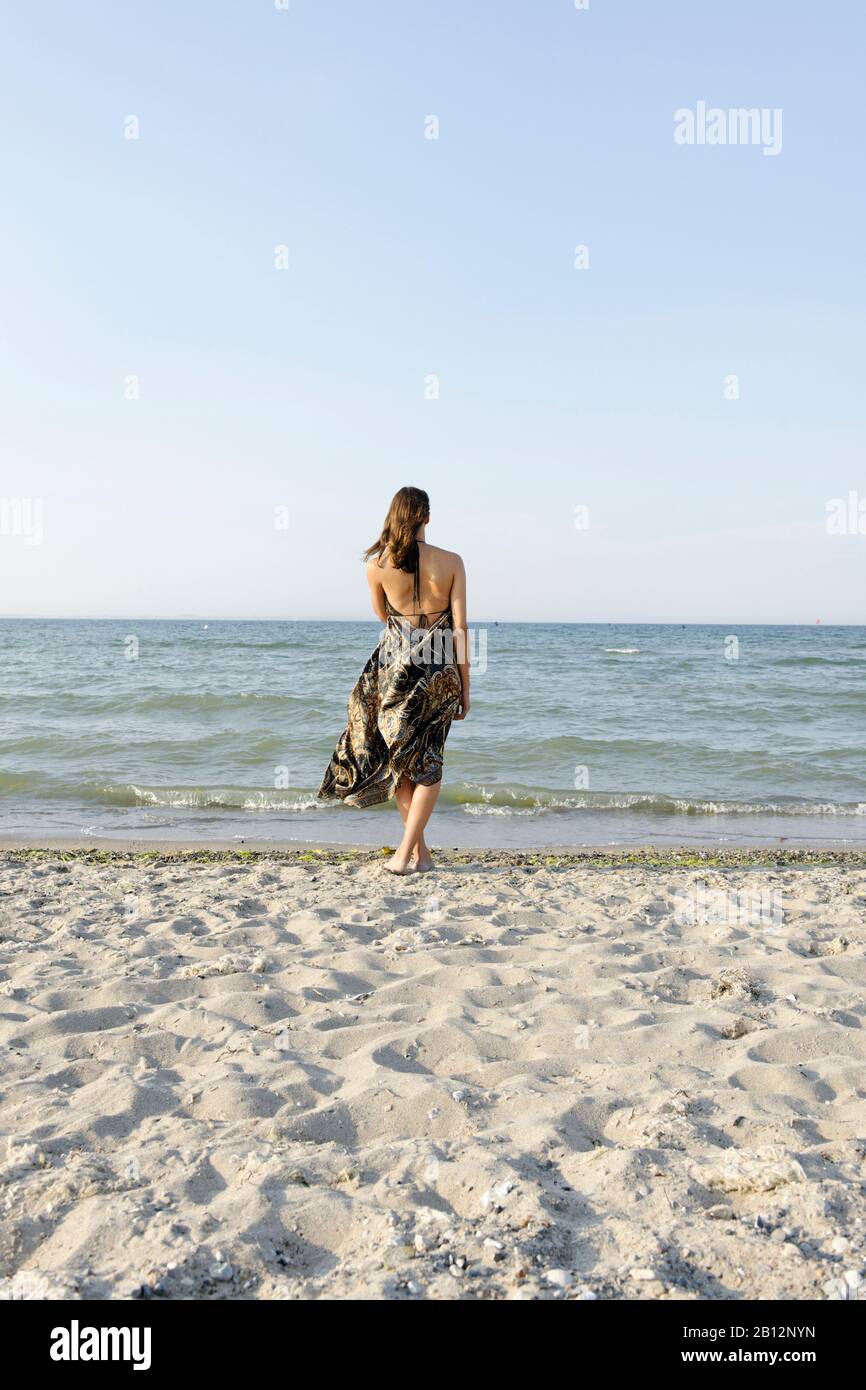 Giovane donna in piedi sulla spiaggia Foto Stock