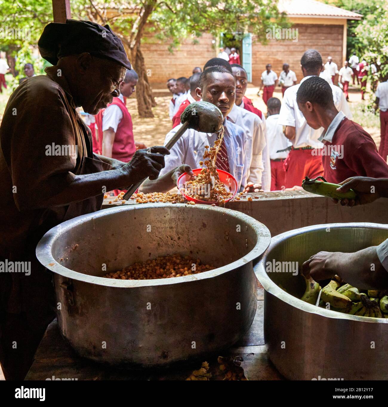 Spendendo lo stufato di ceci e le banane per il pranzo presso la scuola secondaria di un grande ragazzo nel Kenya meridionale Foto Stock