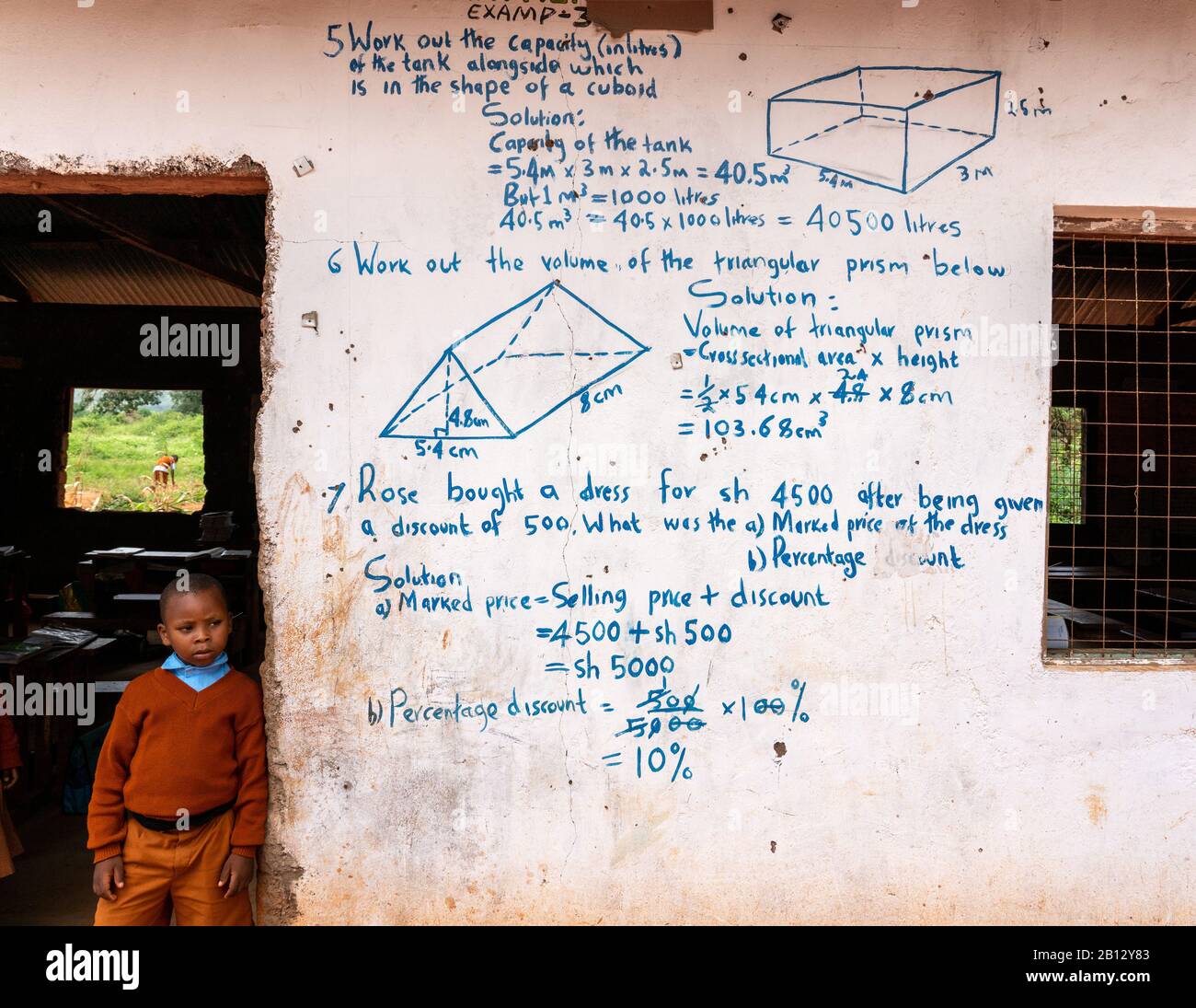 Esercizi di matematica sul muro di una classe in una scuola primaria keniota vicino Al Voi in Africa orientale Foto Stock