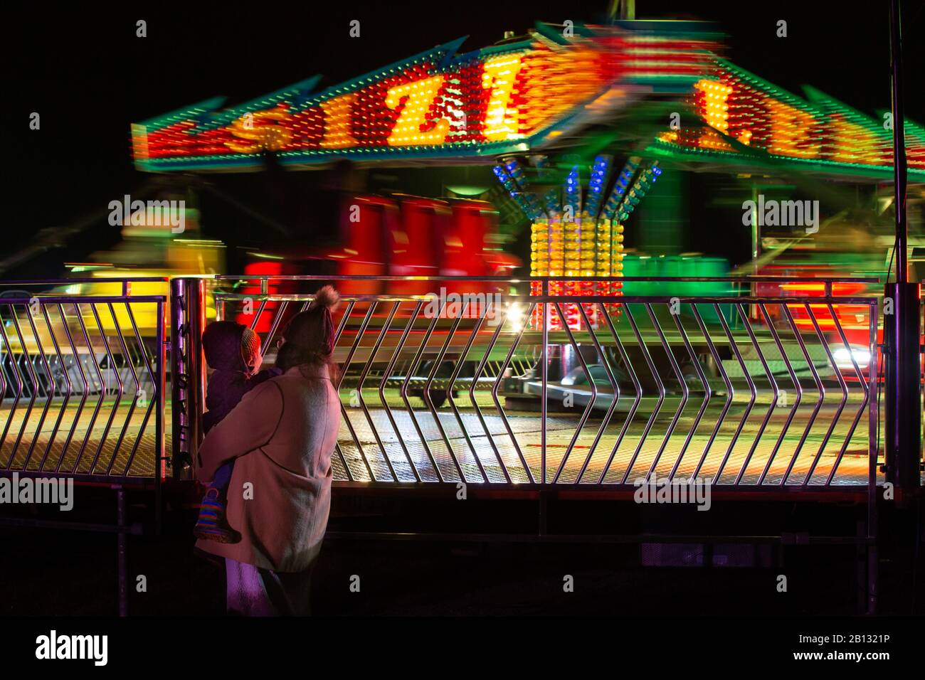 Madre e bambino che si godono le luci sul fairground ride nel buio Foto Stock