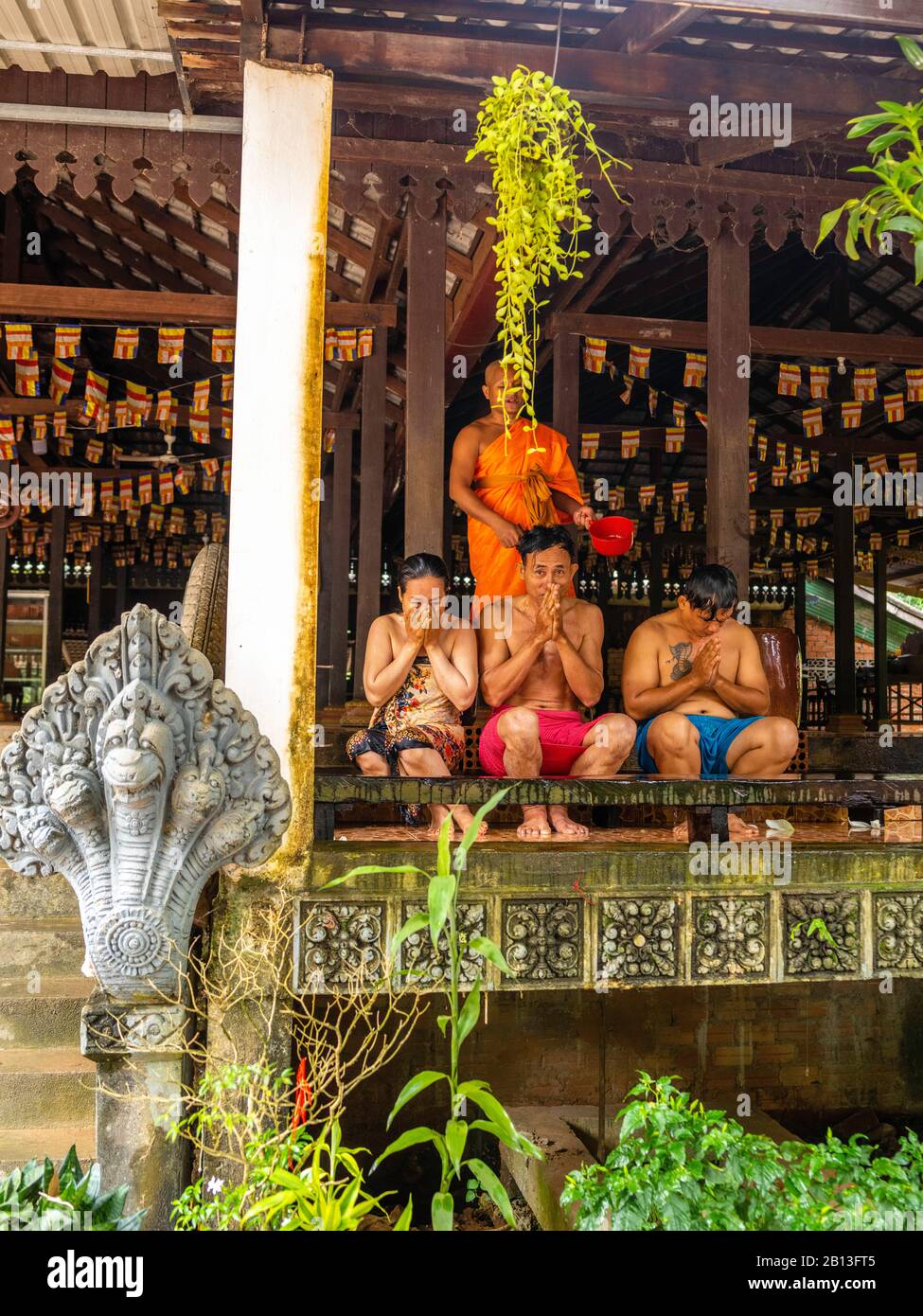 Tre persone ricevono una benedizione d'acqua da un monaco in un tempio buddista della Cambogia durante il Water Festival. Angkor Wat Archeological Park, Siem Reap, C. Foto Stock