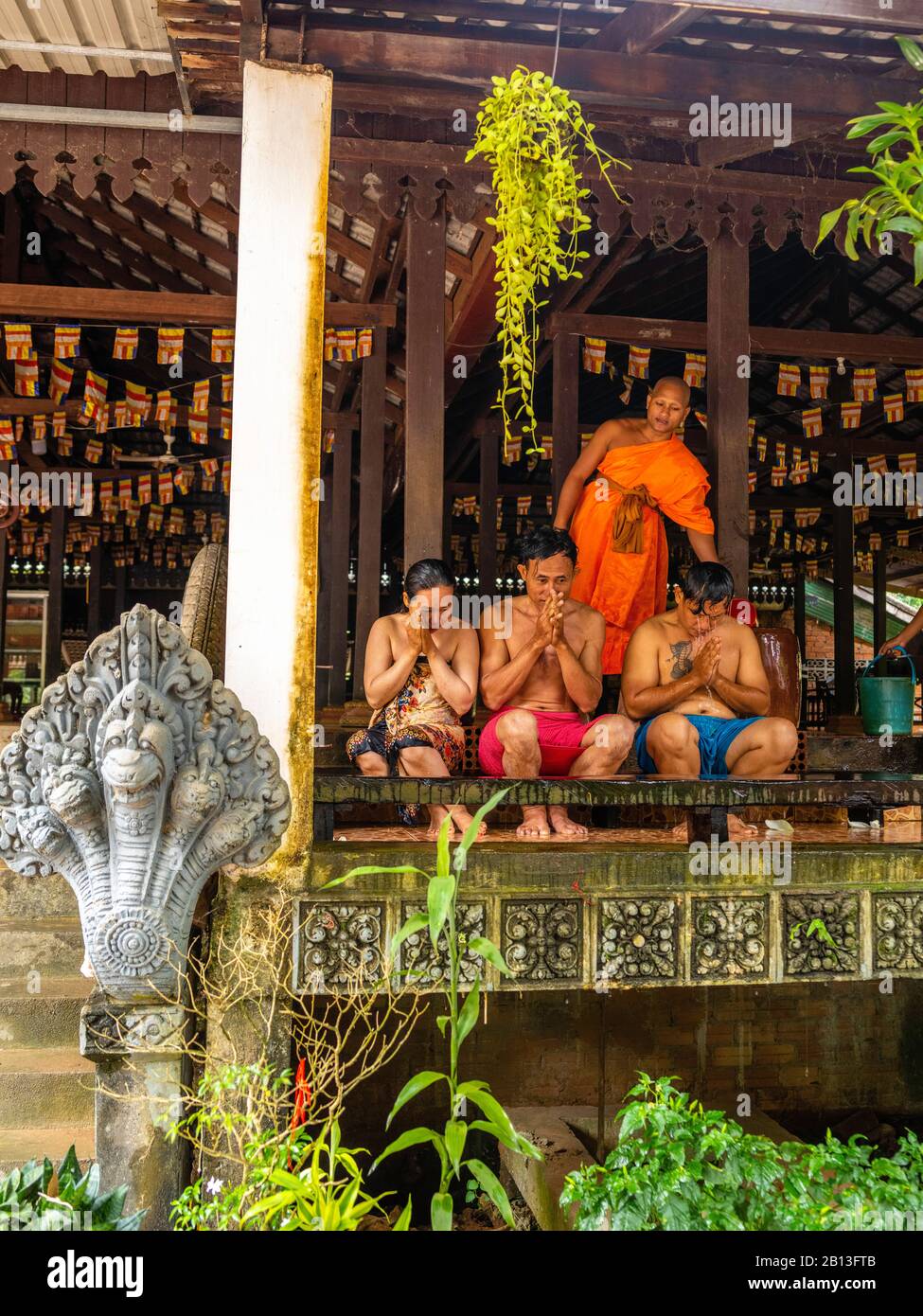 Tre persone ricevono una benedizione d'acqua da un monaco in un tempio buddista della Cambogia durante il Water Festival. Angkor Wat Archeological Park, Siem Reap, C. Foto Stock