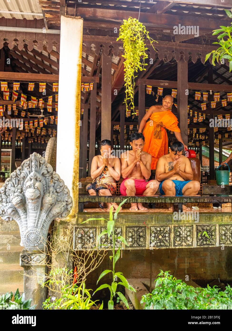 Tre persone ricevono una benedizione da un monaco buddista come parte dell'annuale Water Festival in un tempio all'interno di Angkor Wat Archeological Park, KH Foto Stock