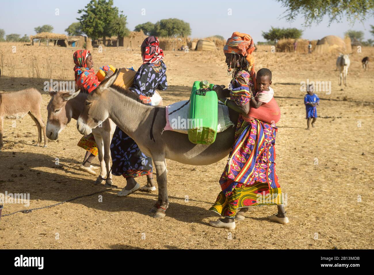 Le donne Fulani raccolgono l'acqua da un buco nel Sahel, Burkina Faso Foto Stock