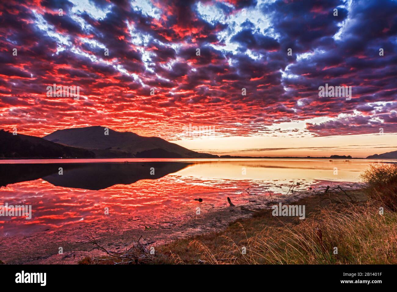 Sole che riflette sulle nuvole all'alba, Hoopers Inlet, Otago Peninsula, Nuova Zelanda Foto Stock