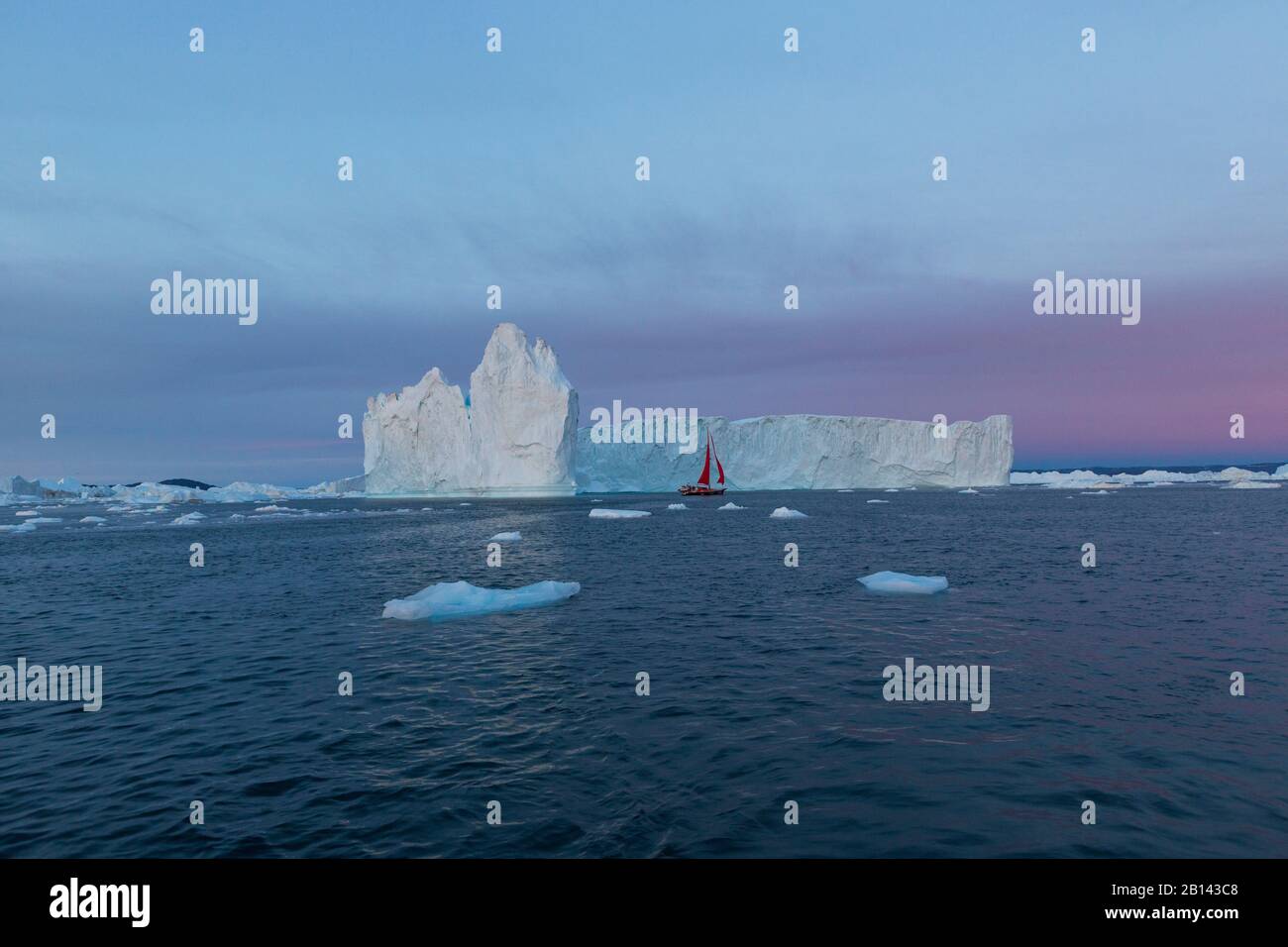 Iceberg e barca a vela nella baia di Disko su Midsummer, Groenlandia Foto Stock