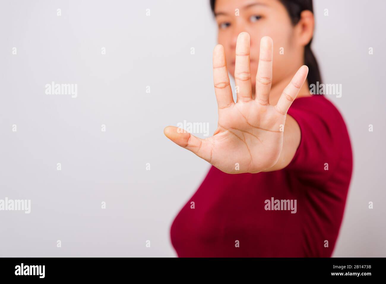 Asian bella donna prurito la sua mano distesa mostrando stop gesture viso anteriore, messa a fuoco sulla mano su sfondo bianco con spazio di copia Foto Stock