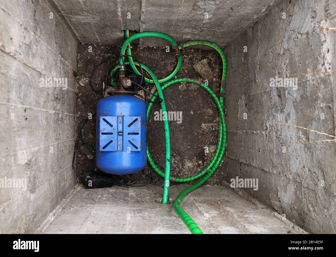 Profonda fossa di calcestruzzo con una stazione di pompaggio dell'acqua per approvvigionamento di acqua a casa. Approvvigionamento idrico domestico. Foto Stock