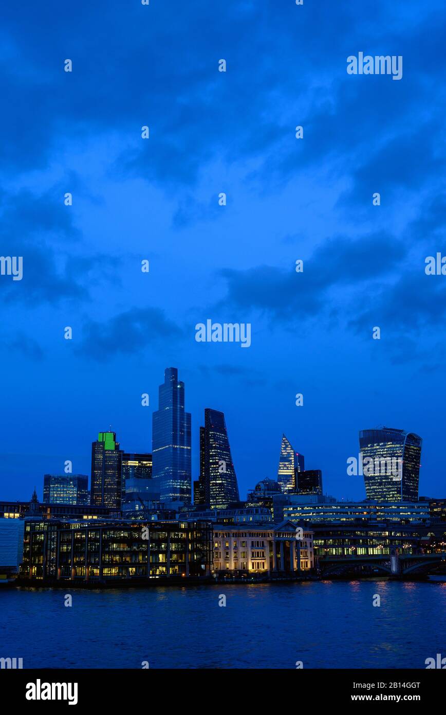 Città di Londra, Regno Unito, con vista sul Tamigi in serata. Paesaggio urbano con grattacieli, luci e cielo blu con nuvole di notte. Londra 2020. Foto Stock