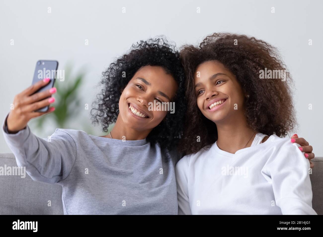 Mamma africana felice con figlia teen prendere selfie sullo smartphone Foto Stock