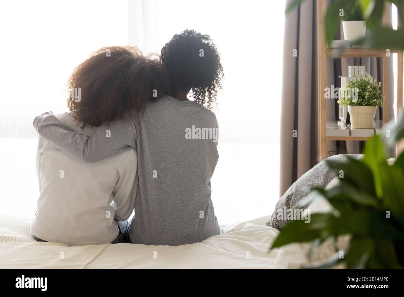 Amorevole madre single africana abbracciare teen figlia sedersi a letto Foto Stock