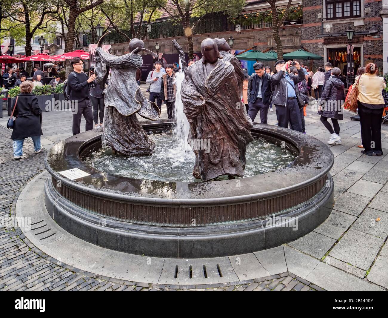 30 novembre 2018: Shanghai, Cina - I Visitatori intorno a una fontana con sculture raffiguranti fortuna, prosperità e longevità, nel quartiere Xintiandi Foto Stock