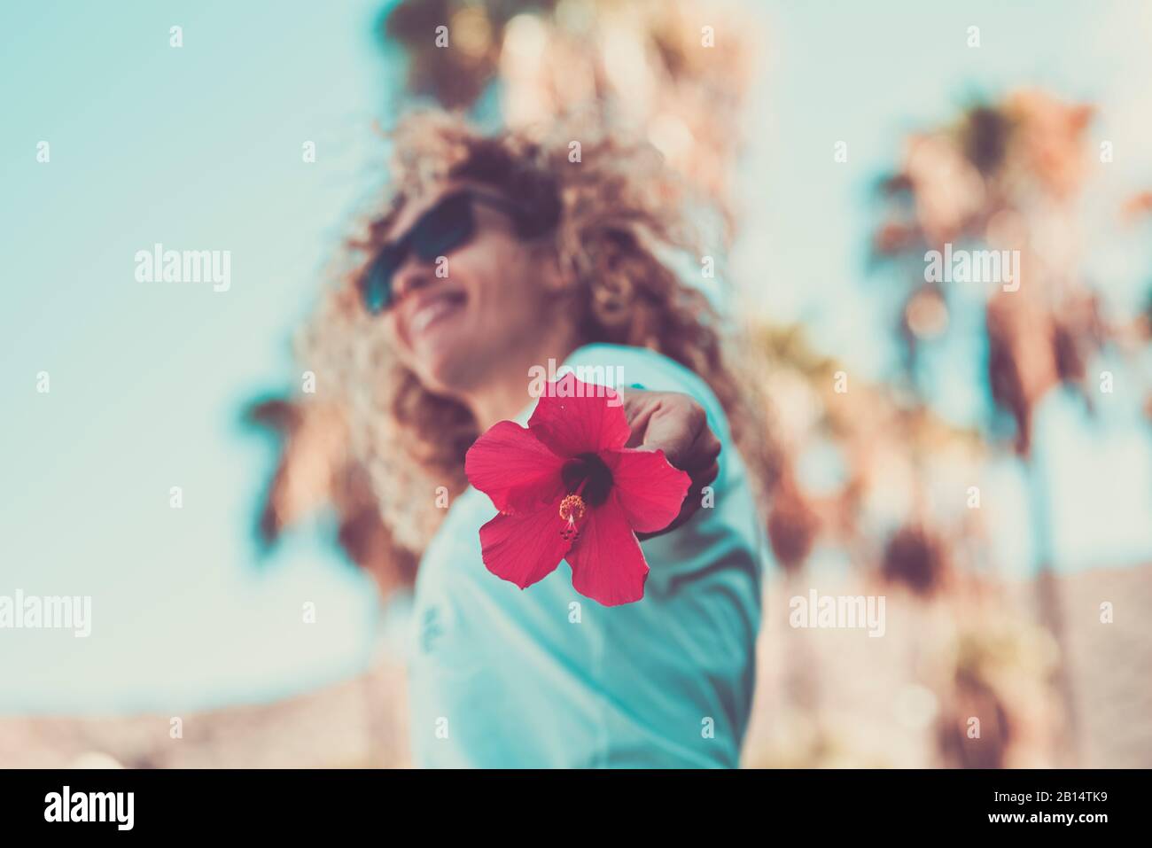 craziness e concetto di felicità con fiore grande rosso in primo piano e danza allegra bella donna in background defocused Foto Stock