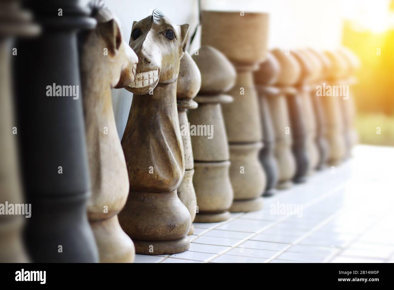 Divertente faccia sul cavaliere degli scacchi in legno. Faccia a faccia cavaliere di scacchi con sorriso toothy. Fuoco selettivo ed effetto di luce caldo Foto Stock