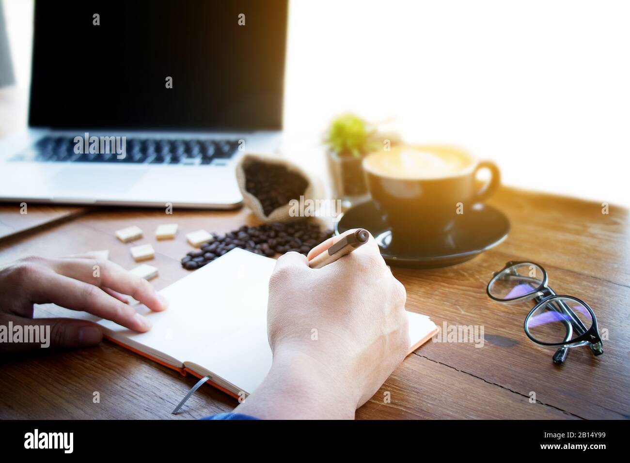 Uomo manager mettere le sue idee e scrivere business plan sul posto di lavoro, uomo tenendo penna e facendo nota in notebook, sul tavolo in ufficio, vintage Foto Stock