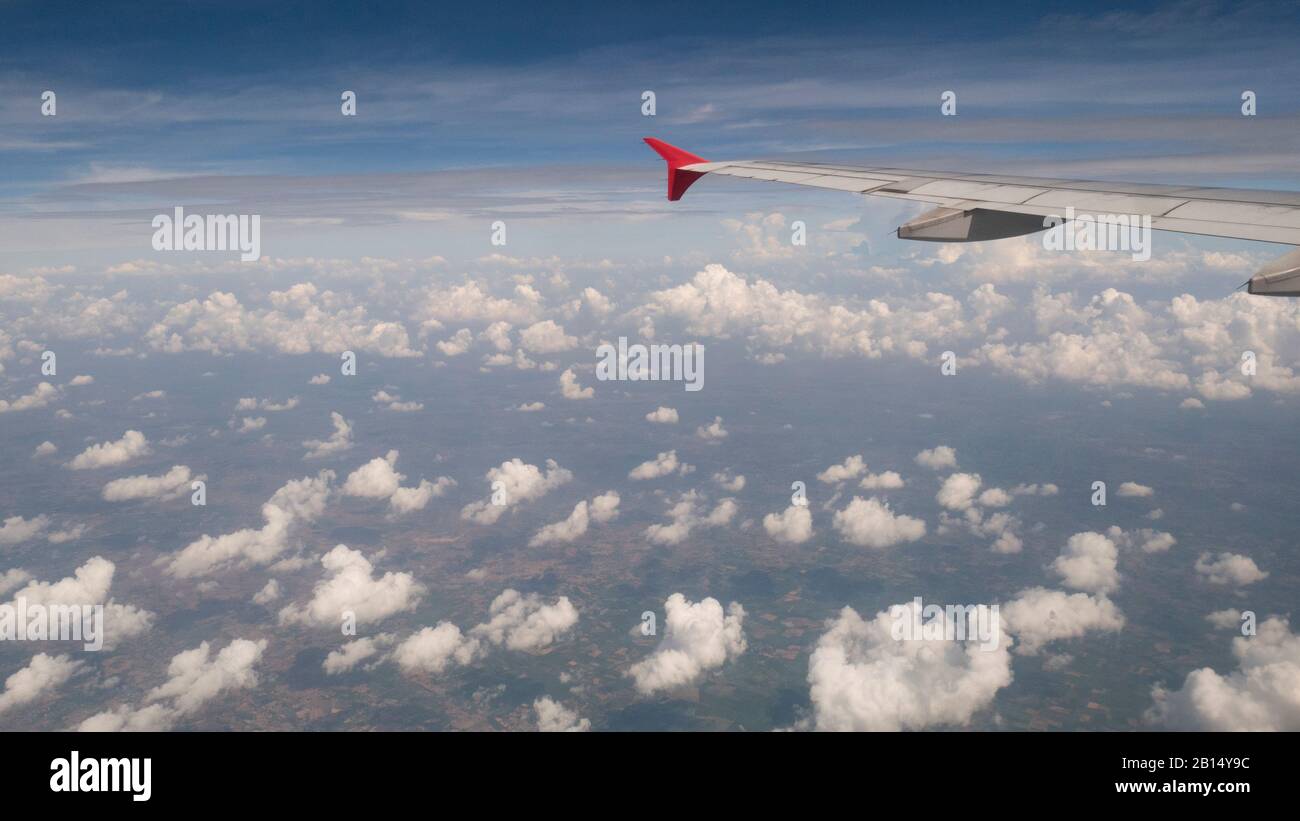 Concetto di viaggio aereo : Vista dalla finestra del velivolo. Nuvole e cielo blu sotto l'ala dell'aeroplano come visto attraverso la finestra di un aeroplano in angelo largo con poliziotto Foto Stock