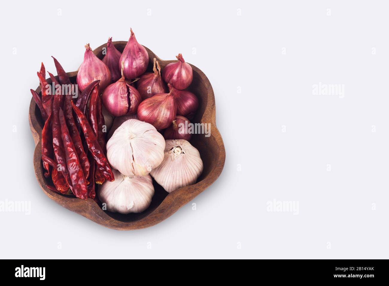 Spezie tailandesi su piastra di legno. I peperoncini secchi, gli scalogni e l'aglio isolano su sfondo bianco con il sentiero di taglio Foto Stock