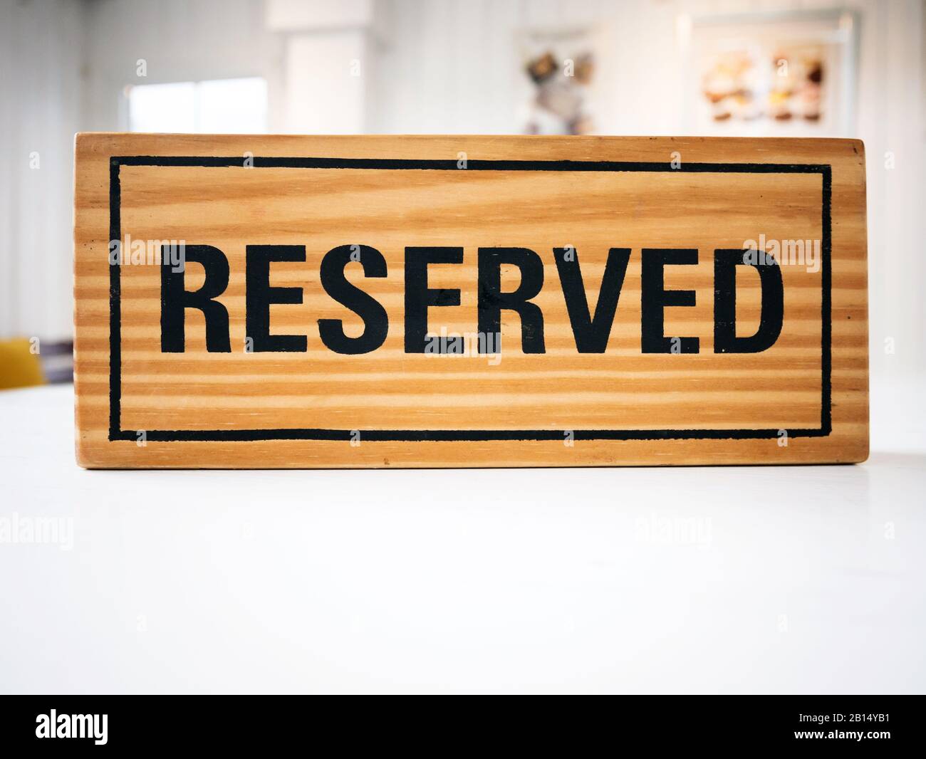Posto a sedere riservato al ristorante per incontri di giorno festeggiato. Ristorante con cartello in legno riservato su tavolo bianco con caffe' che decorano posti a letto Foto Stock