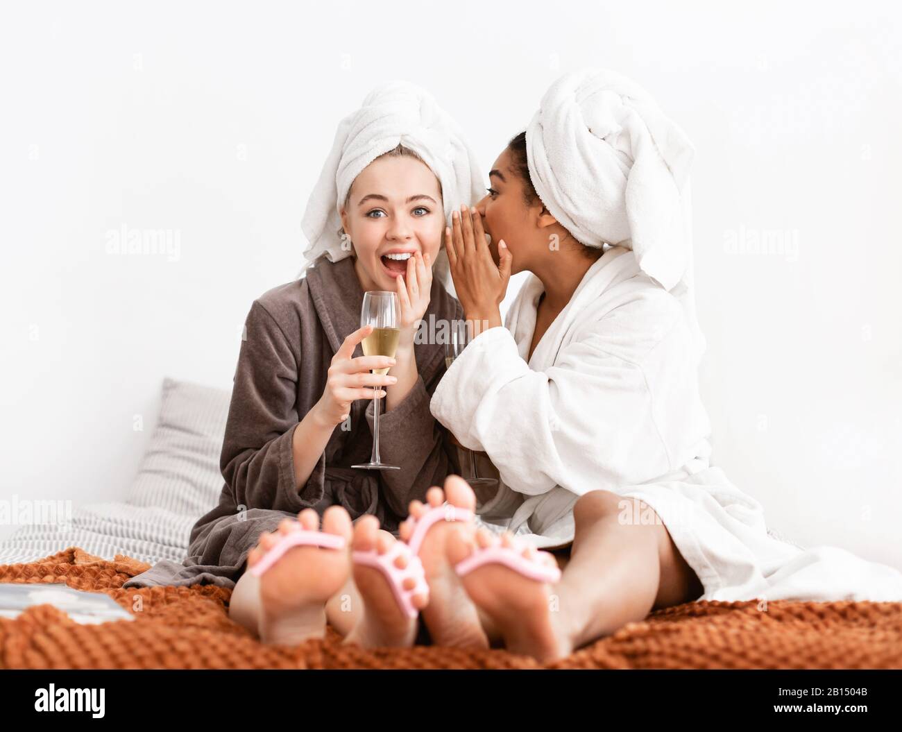 Splendide amiche che condividono i segreti, bevendo champagne mentre si pedicure Foto Stock