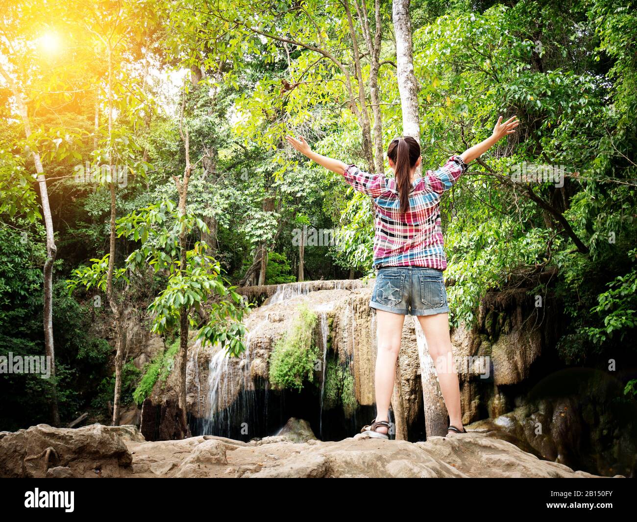 Viaggio vacanza concetto turistico - Felice giovane viaggiatore femminile aprire le braccia con felicità di fronte alla bella cascata con la natura. Avendo un va grande Foto Stock