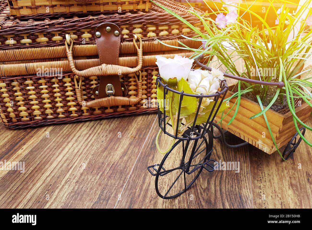 concetto di vacanza estiva. valigia d'epoca sul tavolo decorata con vaso di fiori in forma di piccola bicicletta. copia spazio su tavolo di legno Foto Stock