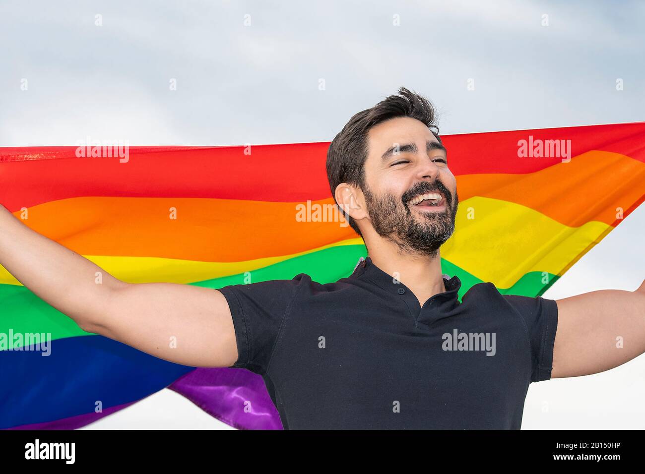 primo piano immagine di ragazzo in piedi con bandiera gay sorridente. concetto di gay, orgoglio, diversità Foto Stock