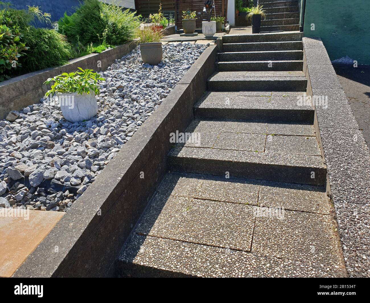Giardino di roccia sterile con vasi di fiori accanto a una scala di cemento lavato, Germania Foto Stock