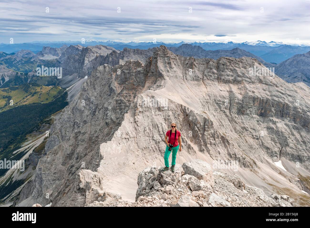 Donna in piedi su rocce e guardando nella macchina fotografica, vista da Birkkarspitze, Karwendeltal, Tirolo, Austria Foto Stock