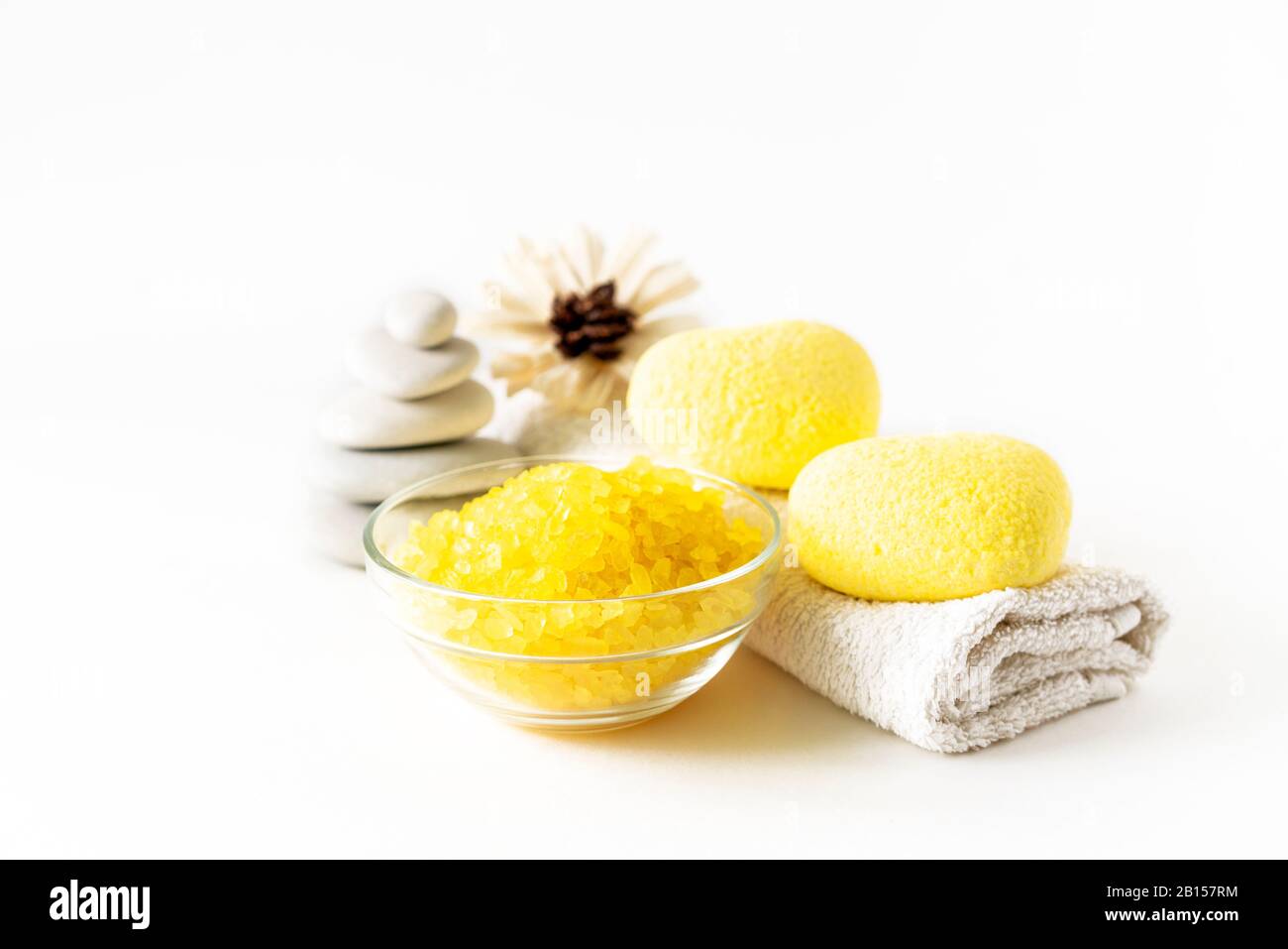 Composizione di prodotti da bagno rilassanti con bombe a forma di cuore giallo, scabra di sale marino, fiori, asciugamani e pietra su sfondo chiaro. Relax, spa e trattamento del corpo. Foto Stock