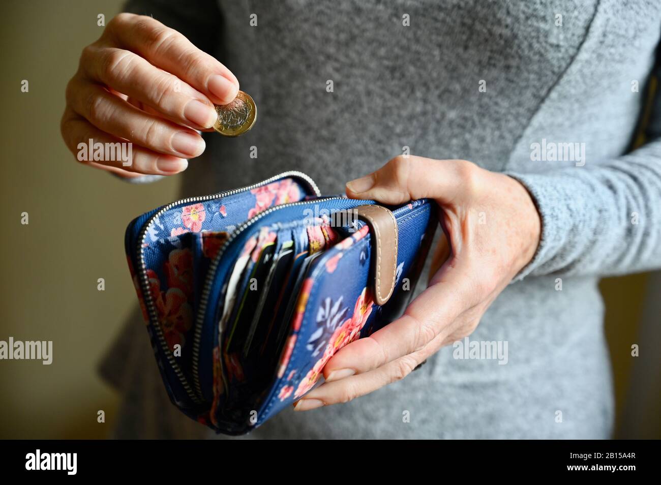 Primo piano di una donna senior che mette una moneta di stagno nella sua borsa. Foto Stock