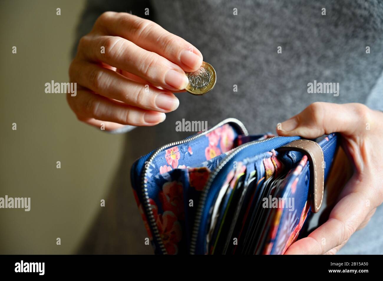 Primo piano di una donna senior che mette una moneta di stagno nella sua borsa. Foto Stock