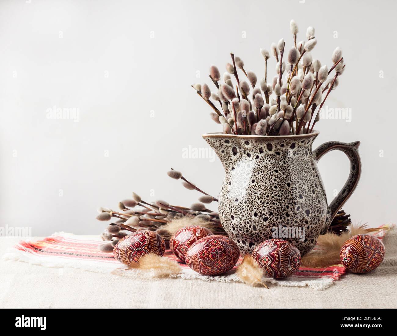 Pasqua ancora vita con Pysanka e salice rami in ceramica brocca su stoffa Ucraina tradizionale. Uova di Pasqua decorate, tradizionali per l'Europa Orientale Foto Stock