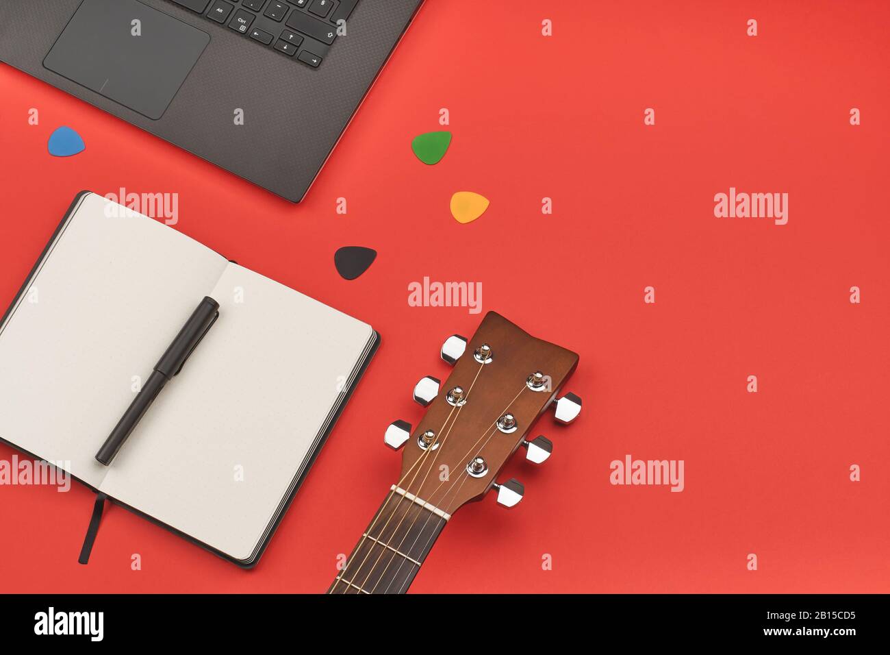 Concetto di apprendimento chitarra online con laptop, notebook e chitarra su sfondo rosso. Vista a pianta piatta minima Foto Stock