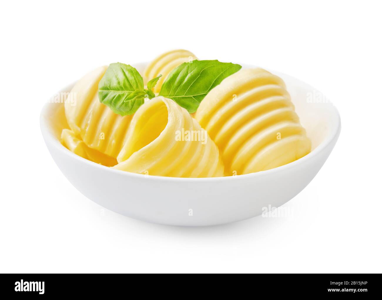 Ricci di burro o involtini di burro in ciotola bianca con foglie di basilico fresco isolato su sfondo bianco. Foto Stock