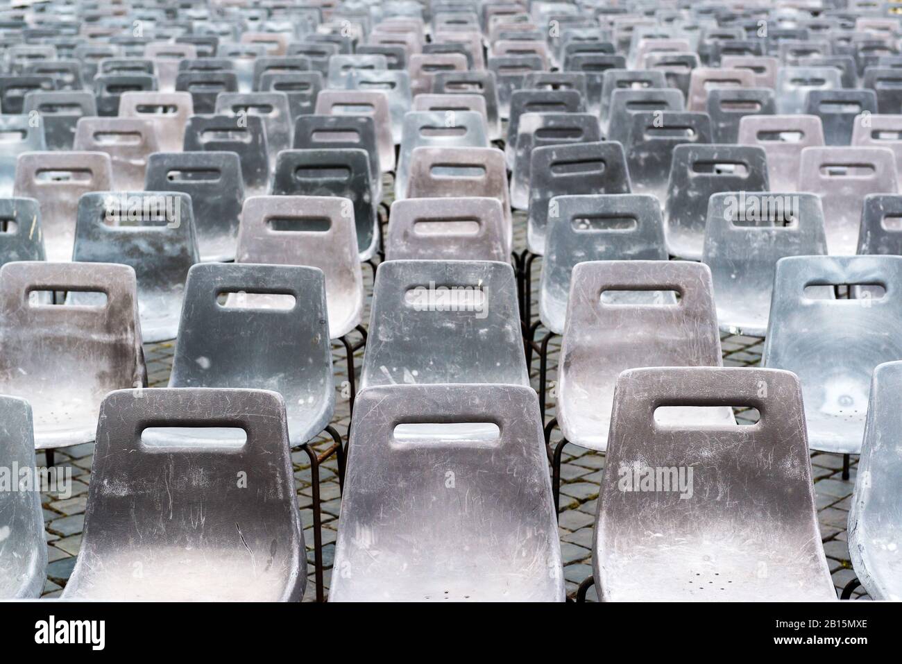 Vecchie sedie grigie vuote in plastica nella piazza della città Foto Stock