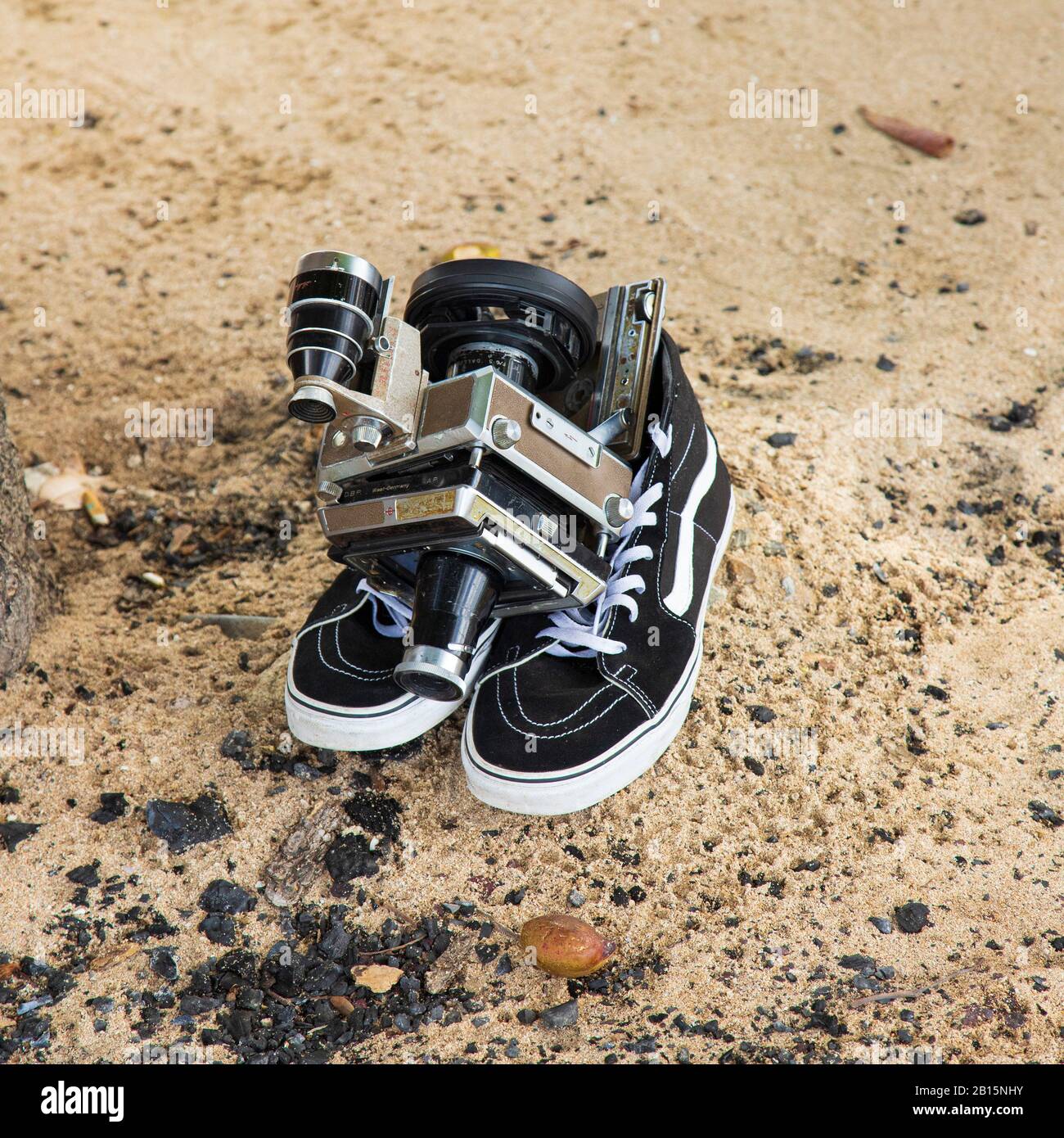 Videocamera Linhof Universal Sucher Technika con zoom e film un paio di moderne sneaker alte su una spiaggia di sabbia Foto Stock