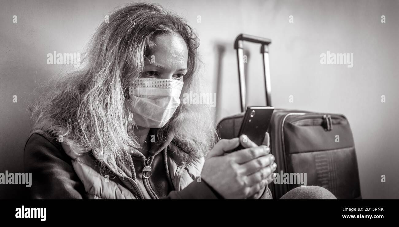 Donna in maschera protettiva si trova vicino al bagaglio in aeroporto. Nuovo focolaio di coronavirus COVID-19, epidemia a Wuhan, Cina. La persona previene l'influenza e la corona v Foto Stock