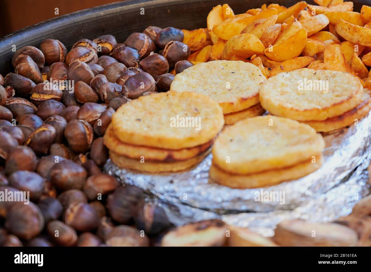 Grande padella su una strada a Vienna per la vendita di cibo, qui piena di frittelle di patate, castagne arrostite e fette di patate Foto Stock