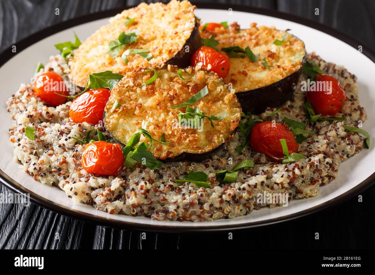 Cibo vegetariano melanzane al forno in pangrattato con un piatto laterale di closeup quinoa su un piatto sul tavolo. Orizzontale Foto Stock