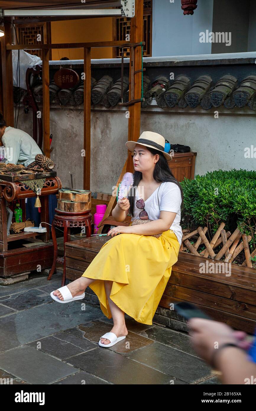 Donna cinese con ventilatore che riposa nel quartiere commerciale Di Chengdu A Vicoli Stretti E Larghi Foto Stock