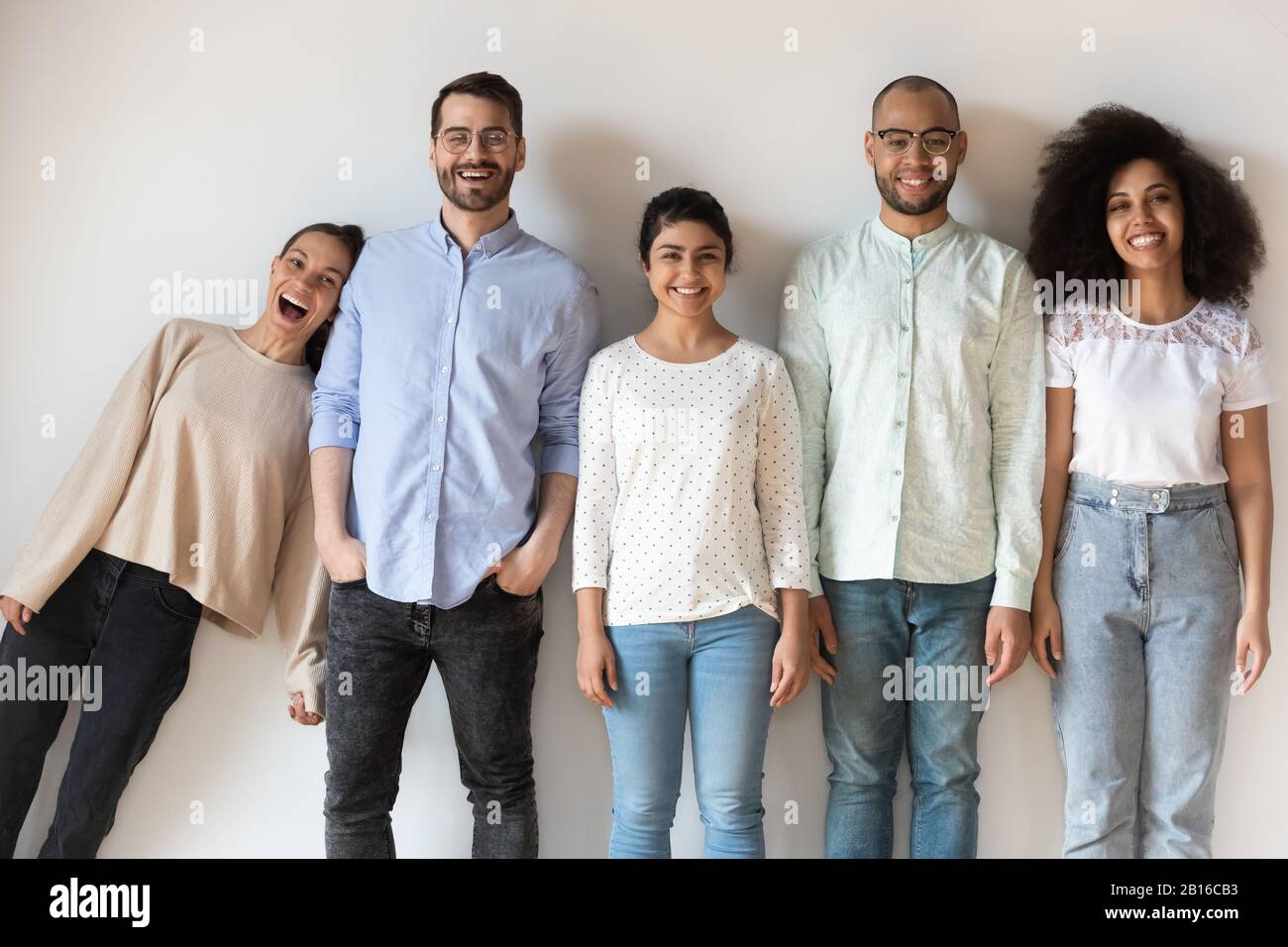 Amici multietnici che si divertono a fare il giro di posa guardando la macchina fotografica Foto Stock