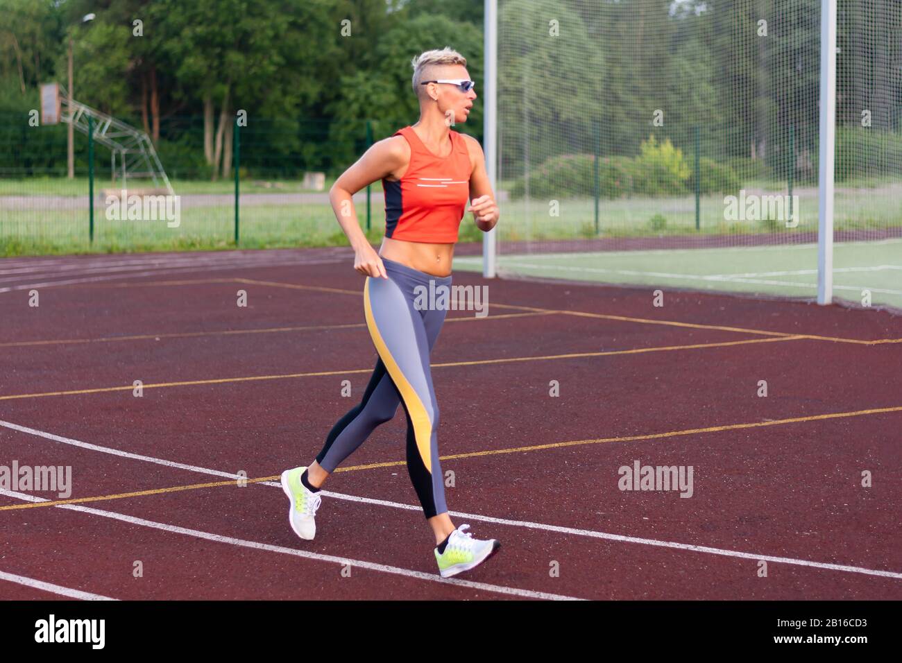 Una donna adulta corre allo stadio, in abiti sportivi. Foto Stock